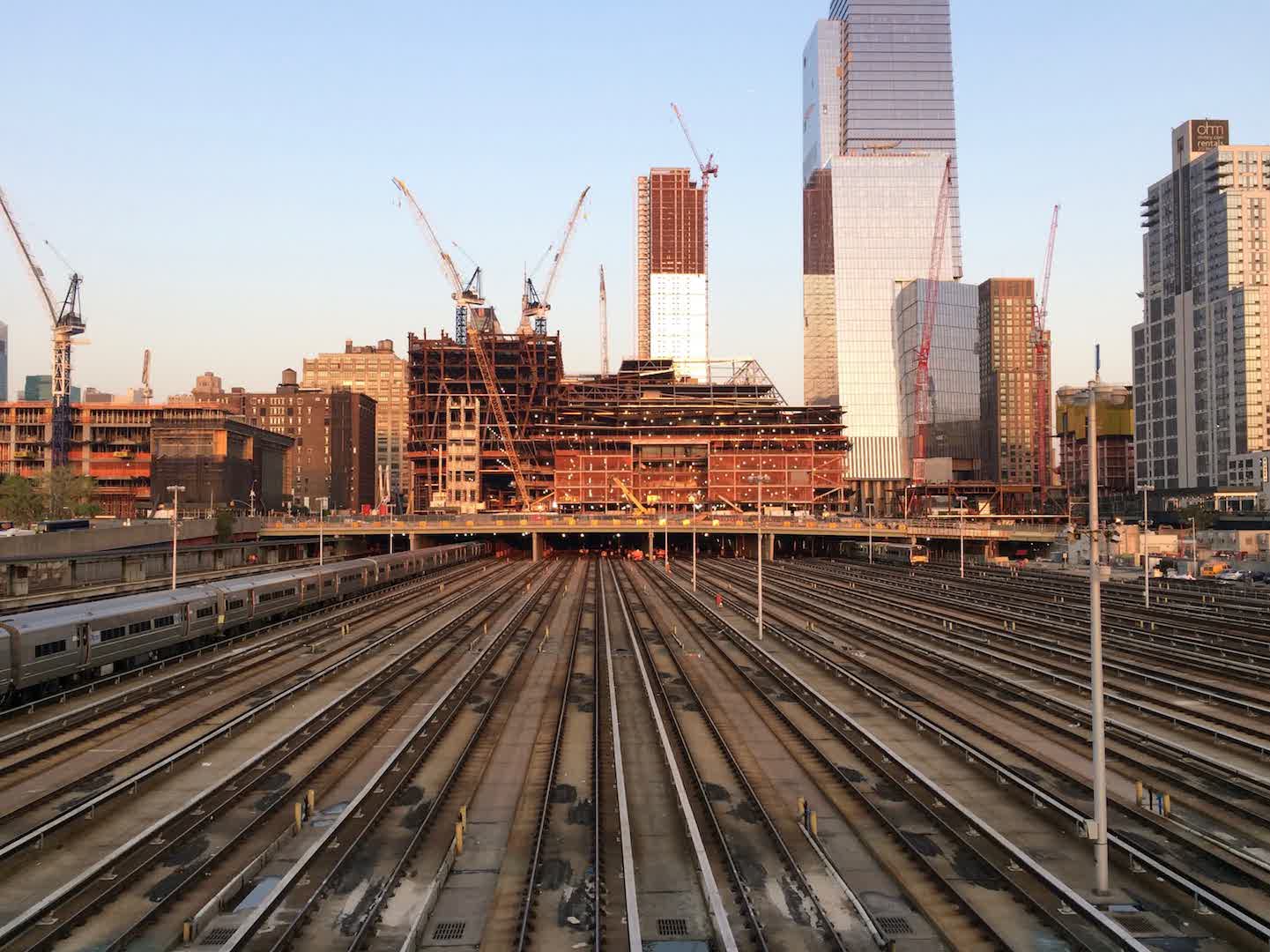 A picture of many parallel subway tracks, with cranes building skyscrapers in the background.