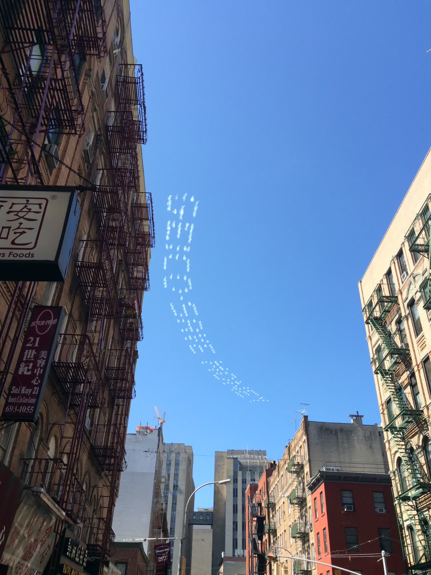 The skies of Chinatown with cloud-like sky-writing from airplanes, reading 'GEICO SAVE MONEY'