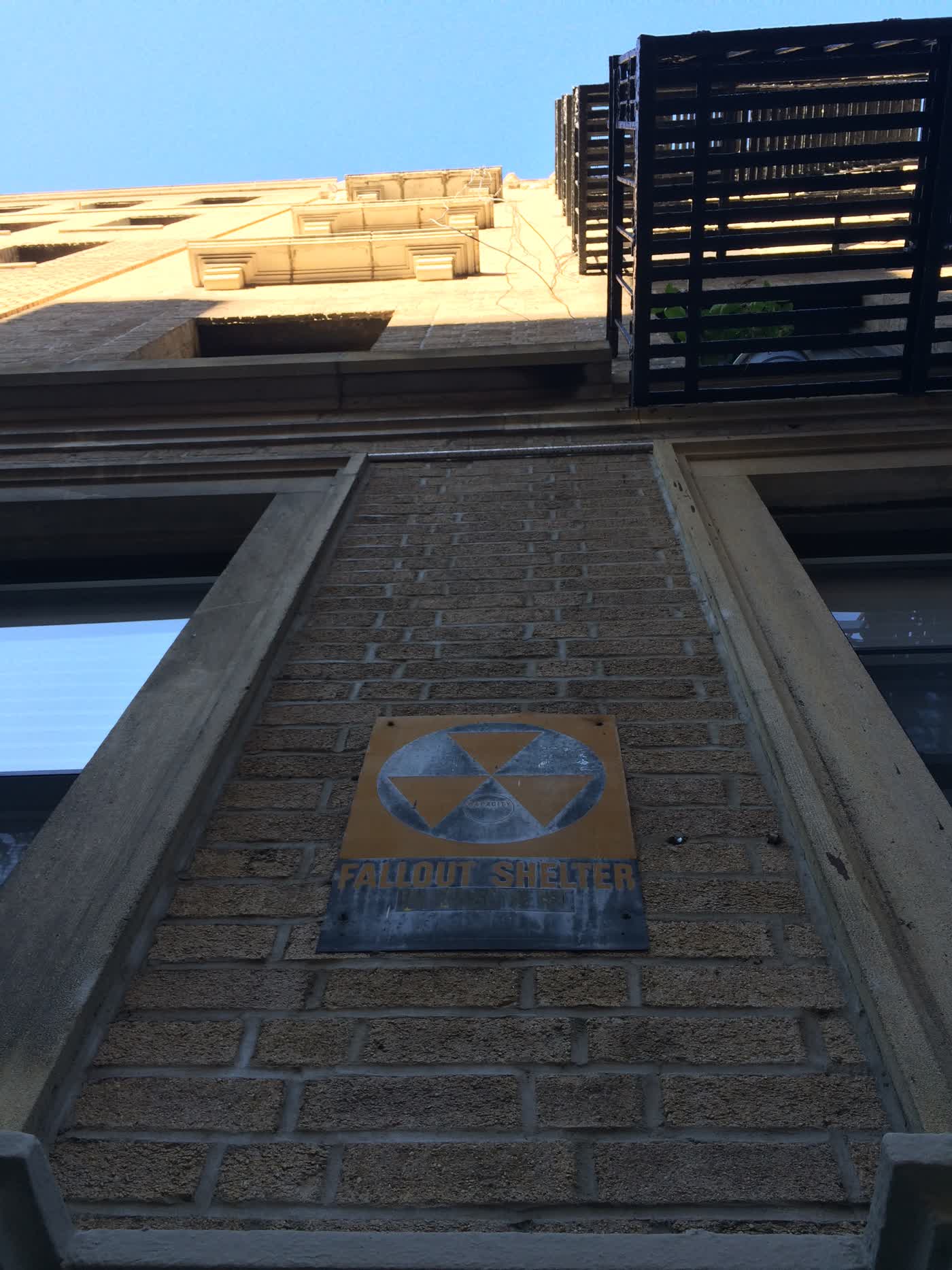 A sign reading 'Fallout Shelter' on the wall of a building.