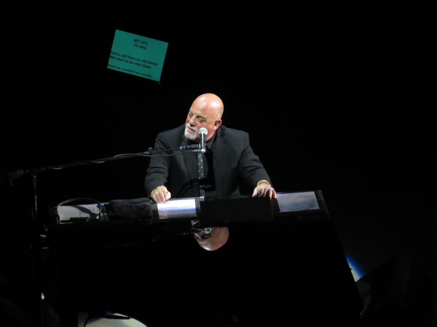Billy Joel on stage, sitting at the piano.